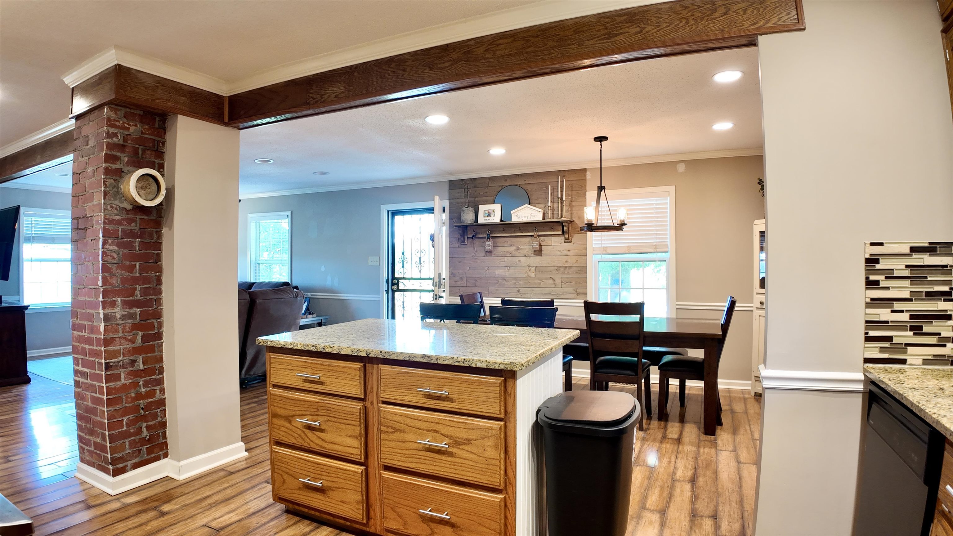3312 Old Memphis Road Covington, TN 38019 - Photo 15 of 32 Kitchen featuring hanging light fixtures, light hardwood / wood-style floors, decorative backsplash, crown molding, and brick wall