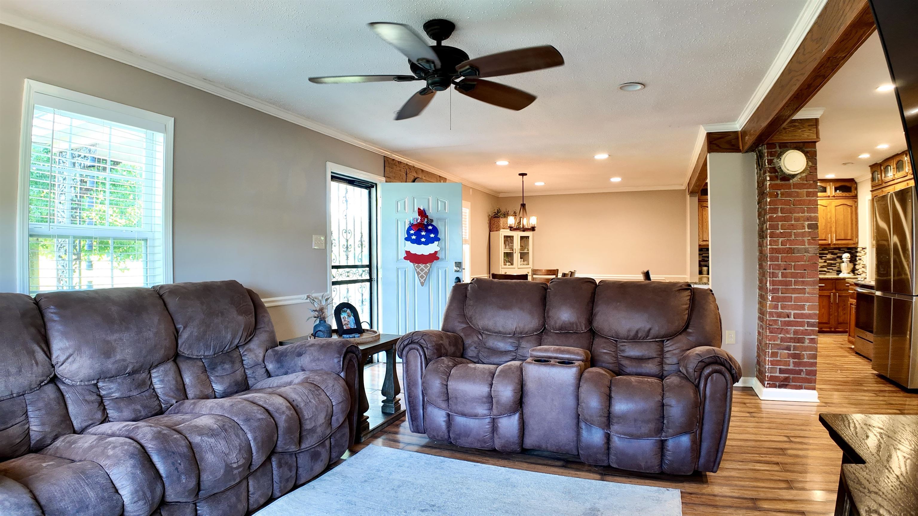 3312 Old Memphis Road Covington, TN 38019 - Photo 18 of 32 Living room with brick wall, ceiling fan with notable chandelier, wood-type flooring, and ornamental molding