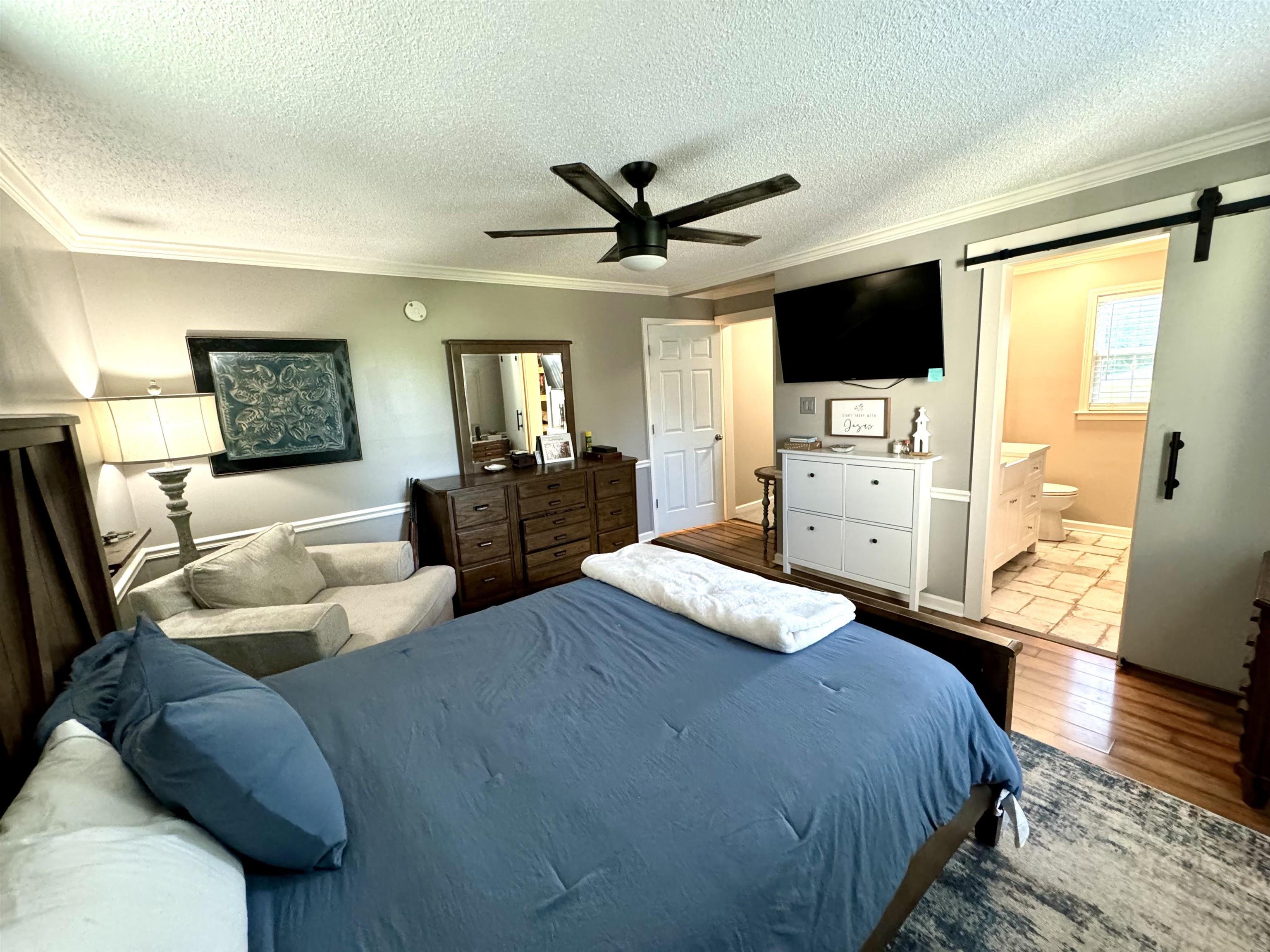 3312 Old Memphis Road Covington, TN 38019 - Photo 21 of 32 Bedroom with ceiling fan, crown molding, a barn door, light hardwood / wood-style flooring, and ensuite bathroom