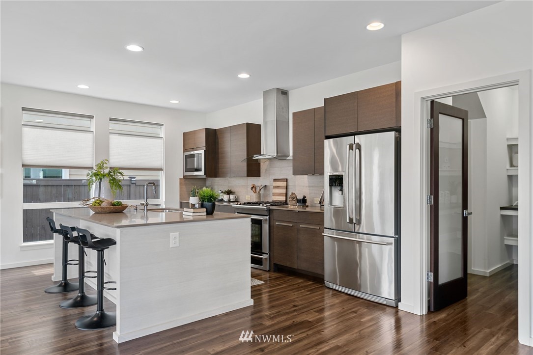 17223 40th Avenue Southeast Bothell, WA 98012 - Photo 11 of 37 a kitchen with kitchen island a refrigerator a stove a sink and white cabinets with wooden floor