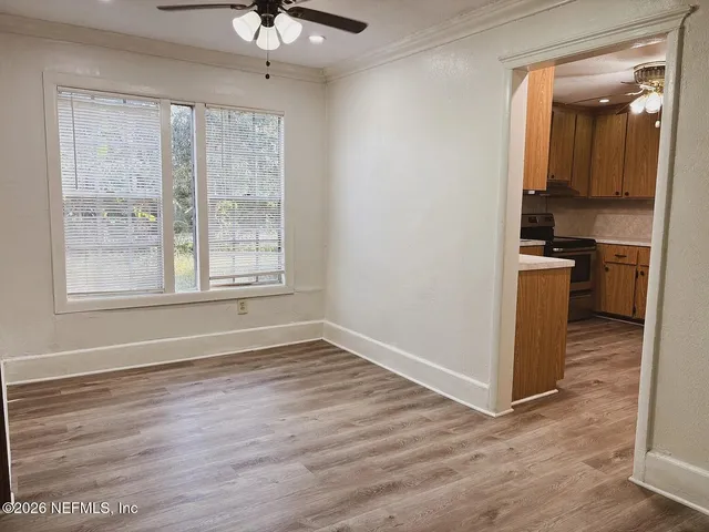 a view of a kitchen with a stove cabinets a ceiling fan and wooden floor