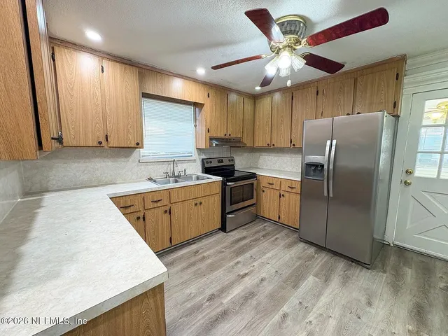 a kitchen with stainless steel appliances granite countertop a sink a stove a refrigerator cabinets and wooden floor