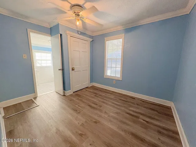 an empty room with wooden floor fan and windows
