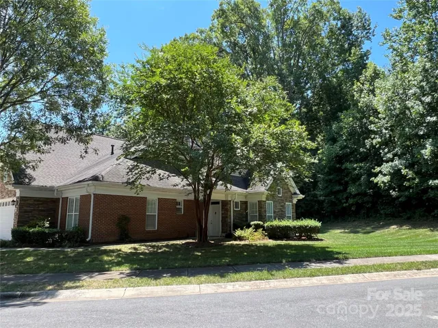a front view of a house with a garden and trees