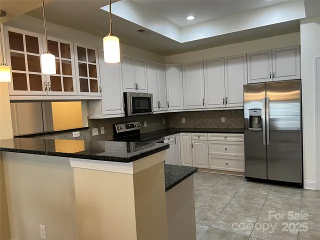 a kitchen with stainless steel appliances granite countertop a refrigerator a stove a sink and a microwave