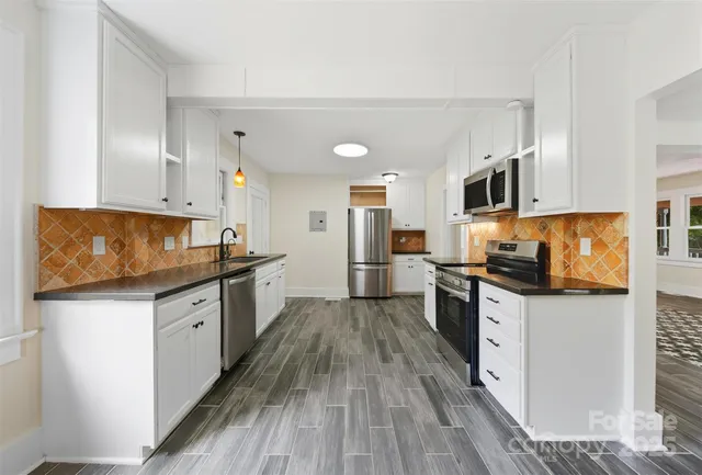 a kitchen with granite countertop a sink cabinets stainless steel appliances and a counter space