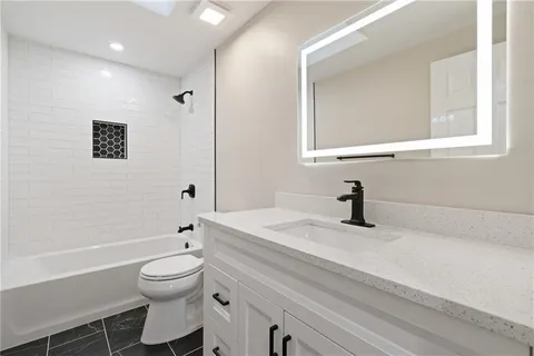 a bathroom with a granite countertop sink a toilet and a bathtub