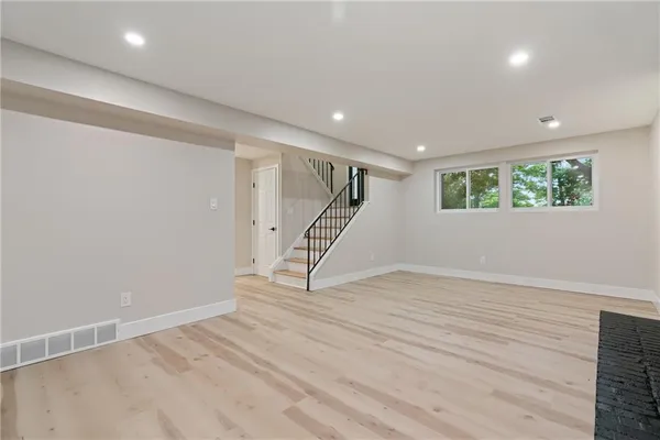 a view of an empty room with wooden floor and stairs