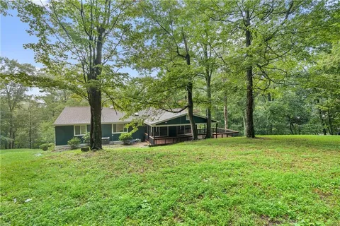 a view of a house with a big yard and large trees