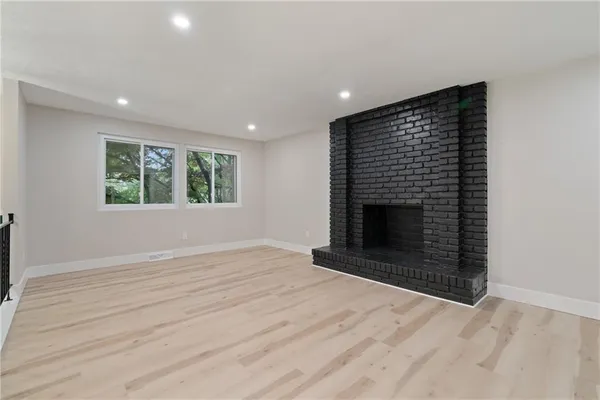 an empty room with windows and fireplace