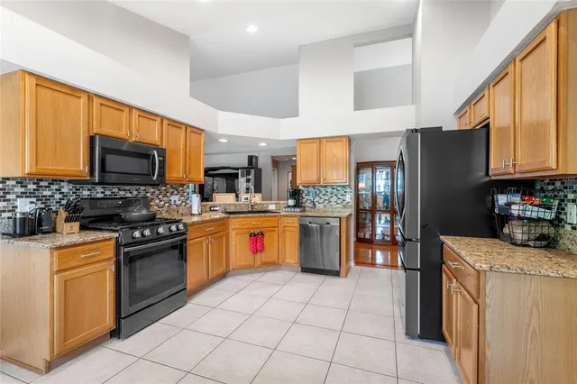 a kitchen with stainless steel appliances granite countertop a refrigerator a stove top oven a sink dishwasher and white cabinets