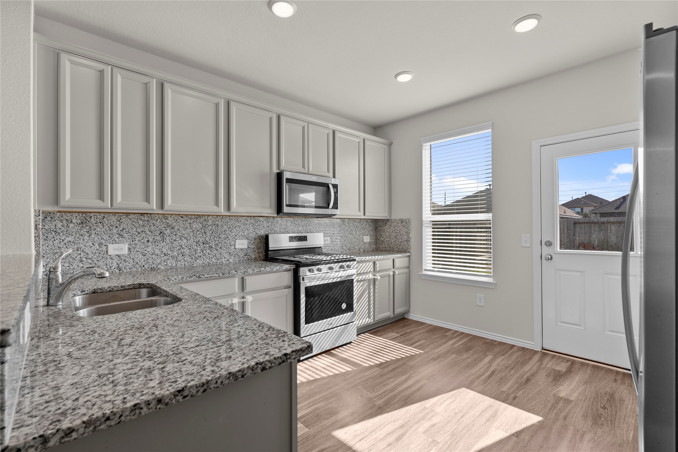 25639 Royal Catchfly Road Katy, TX 77493 - Photo 14 of 48 a kitchen with granite countertop a stove a sink and a microwave