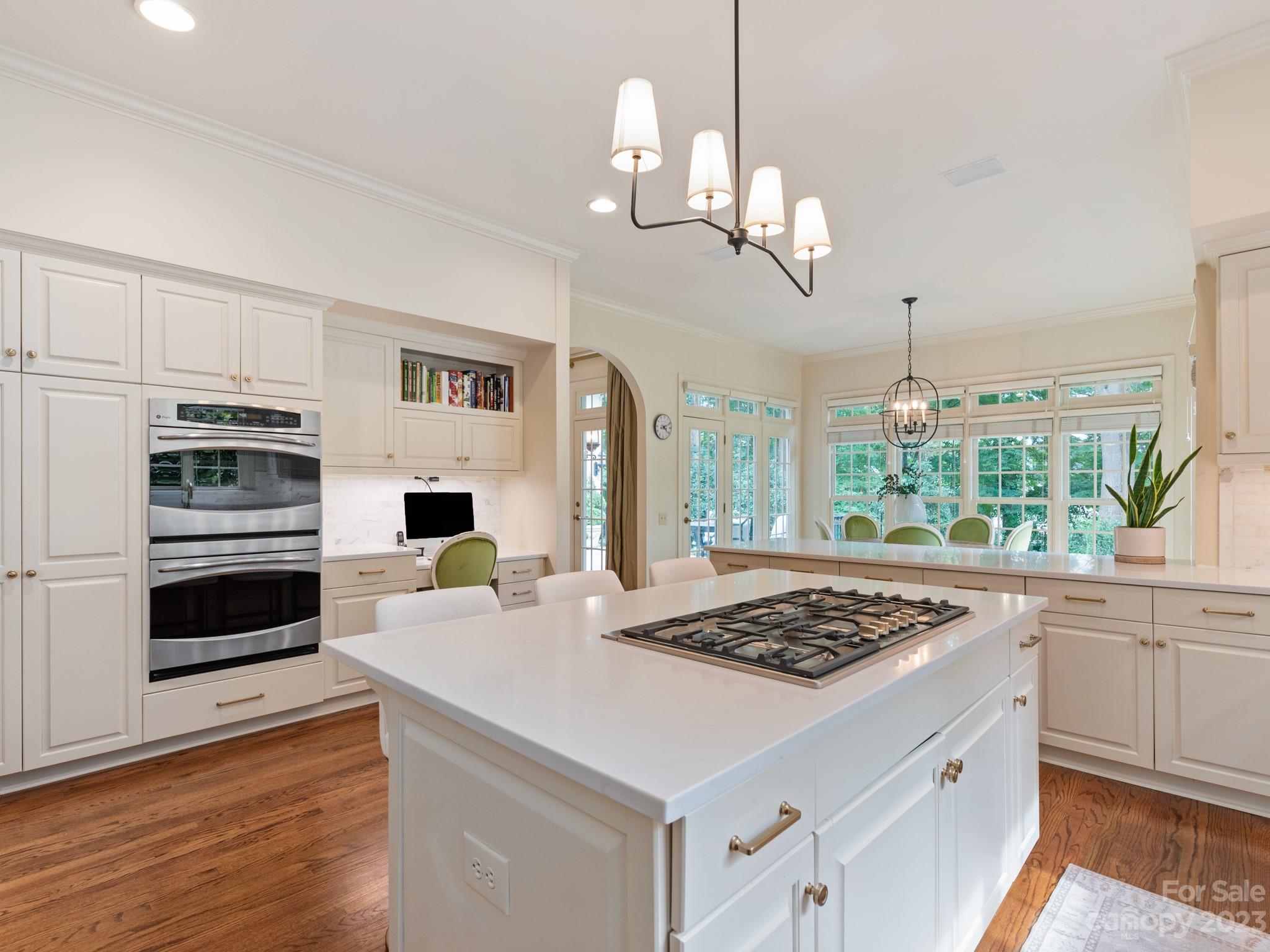 2521 Summerlake Road Charlotte, NC 28226 - Photo 19 of 48 a kitchen with a stove a sink a kitchen island with windows and wooden floor