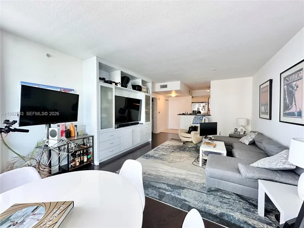 a living room with furniture a flat screen tv and kitchen view