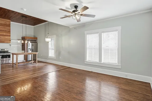 a view of an empty room with wooden floor and a window