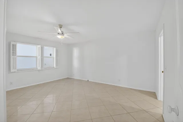 an empty room with chandelier fan and windows
