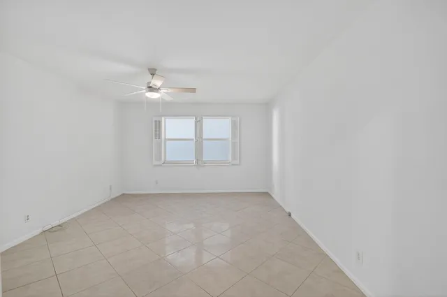 an empty room with windows and ceiling fan