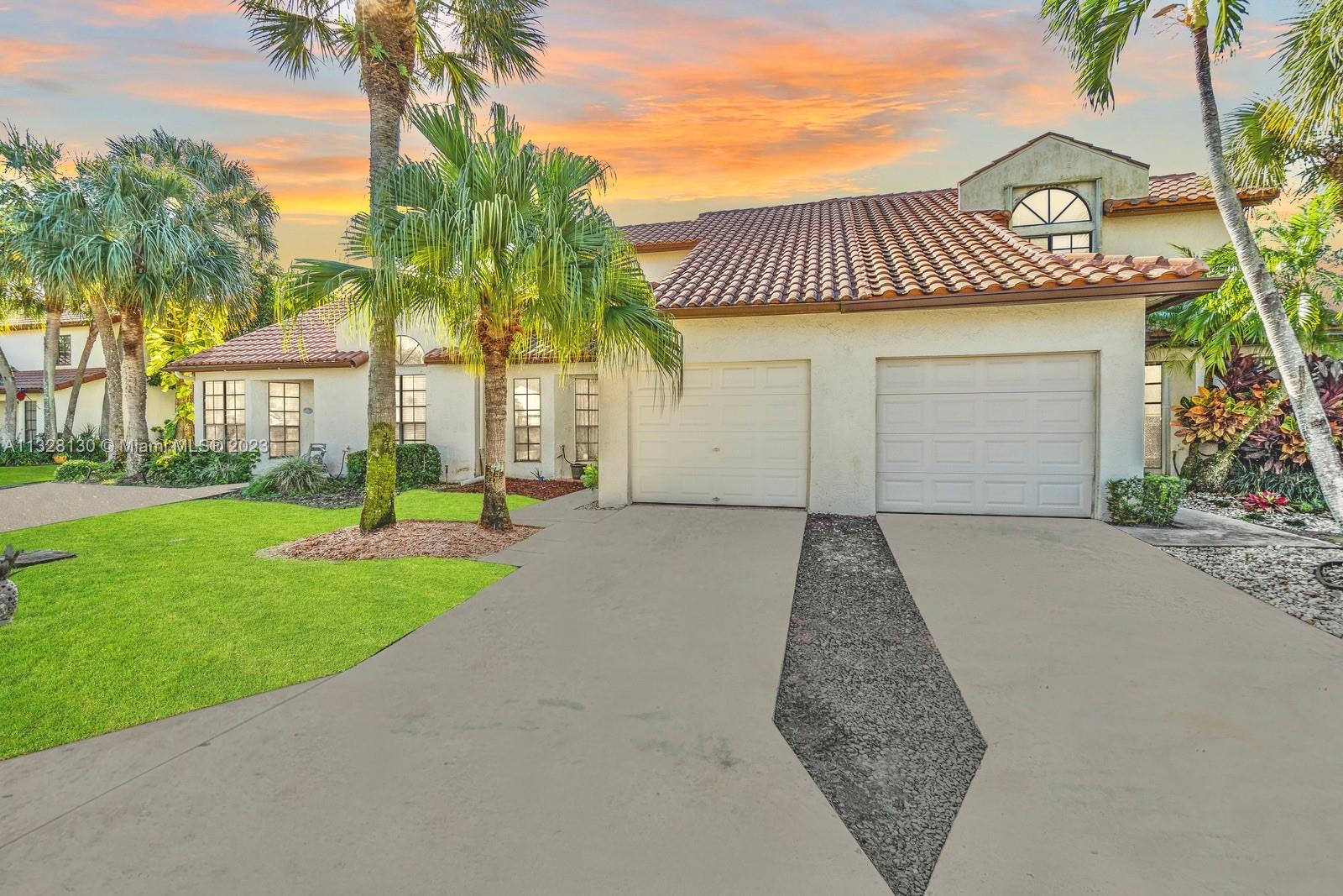 a view of a house with a yard and palm trees