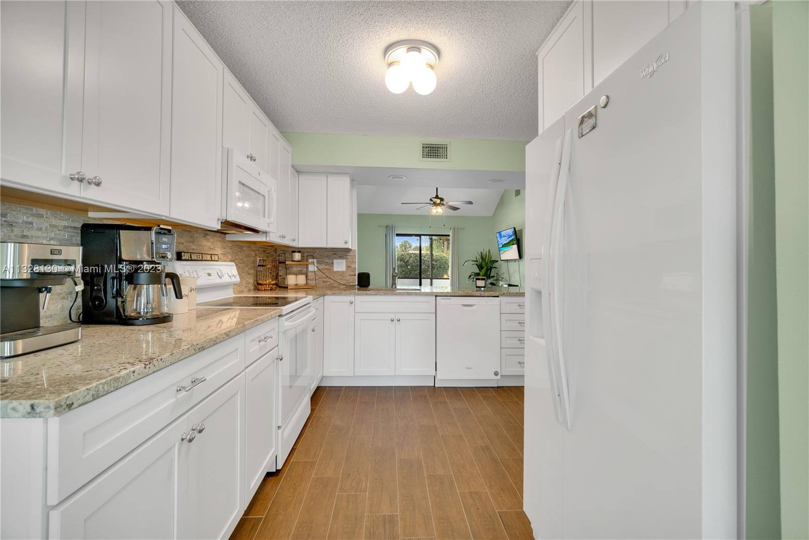 10274 Windswept Place Boca Raton, FL 33498 - Photo 5 of 33 a kitchen with granite countertop white cabinets and white appliances