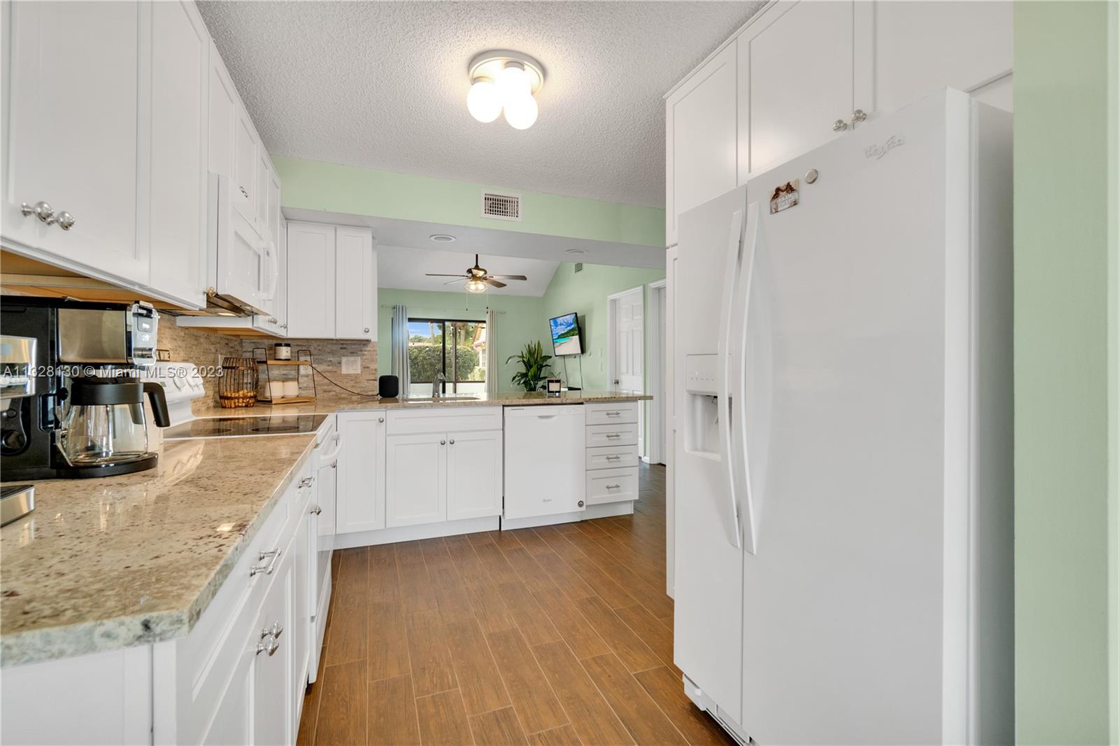 10274 Windswept Place Boca Raton, FL 33498 - Photo 6 of 33 a kitchen with stainless steel appliances granite countertop a refrigerator a sink dishwasher a stove and white cabinets with wooden floor