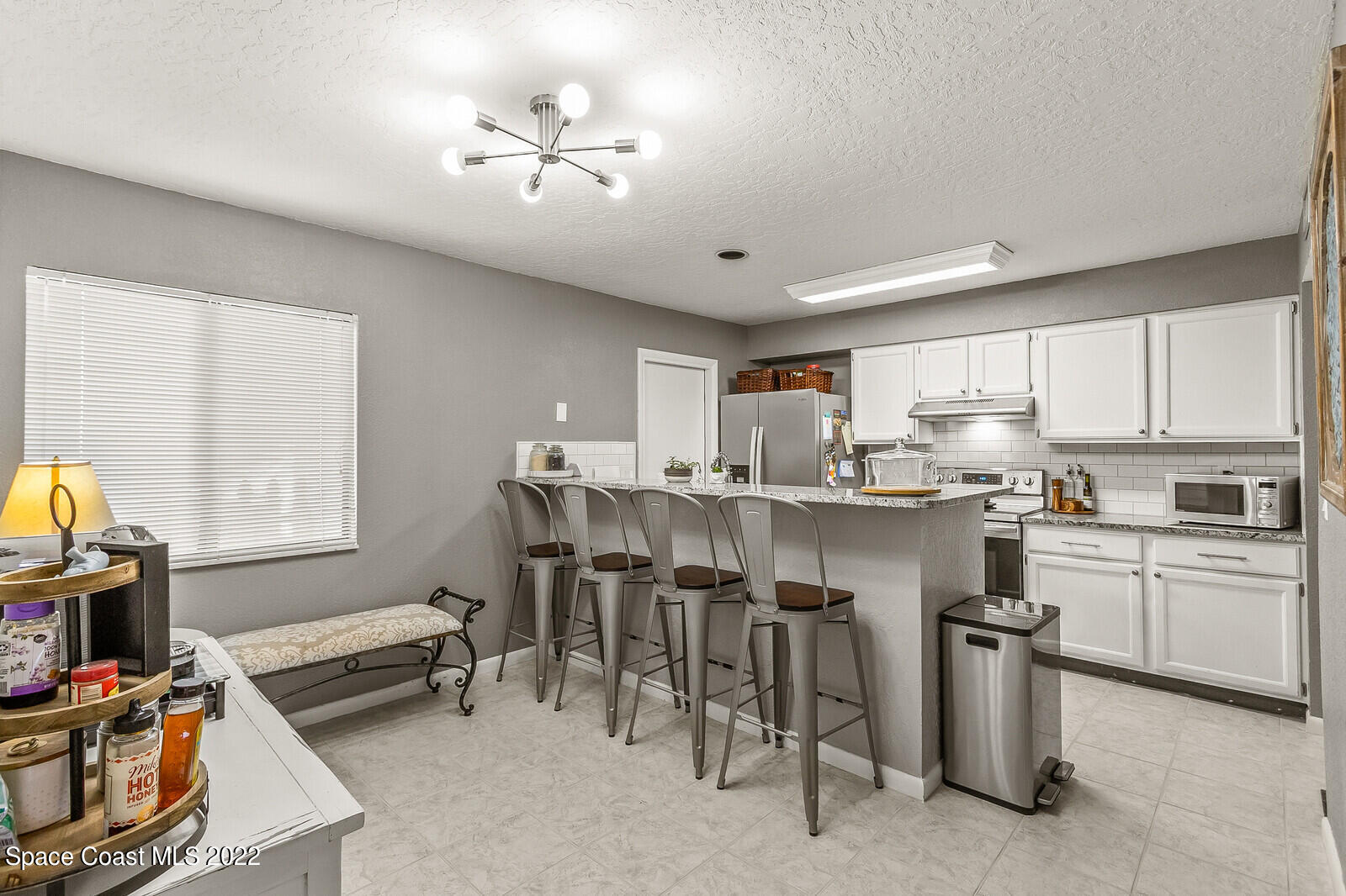 1784 Quail Trail Melbourne, FL 32935 - Photo 13 of 40 a kitchen with kitchen island a stove a sink a dining table and chairs