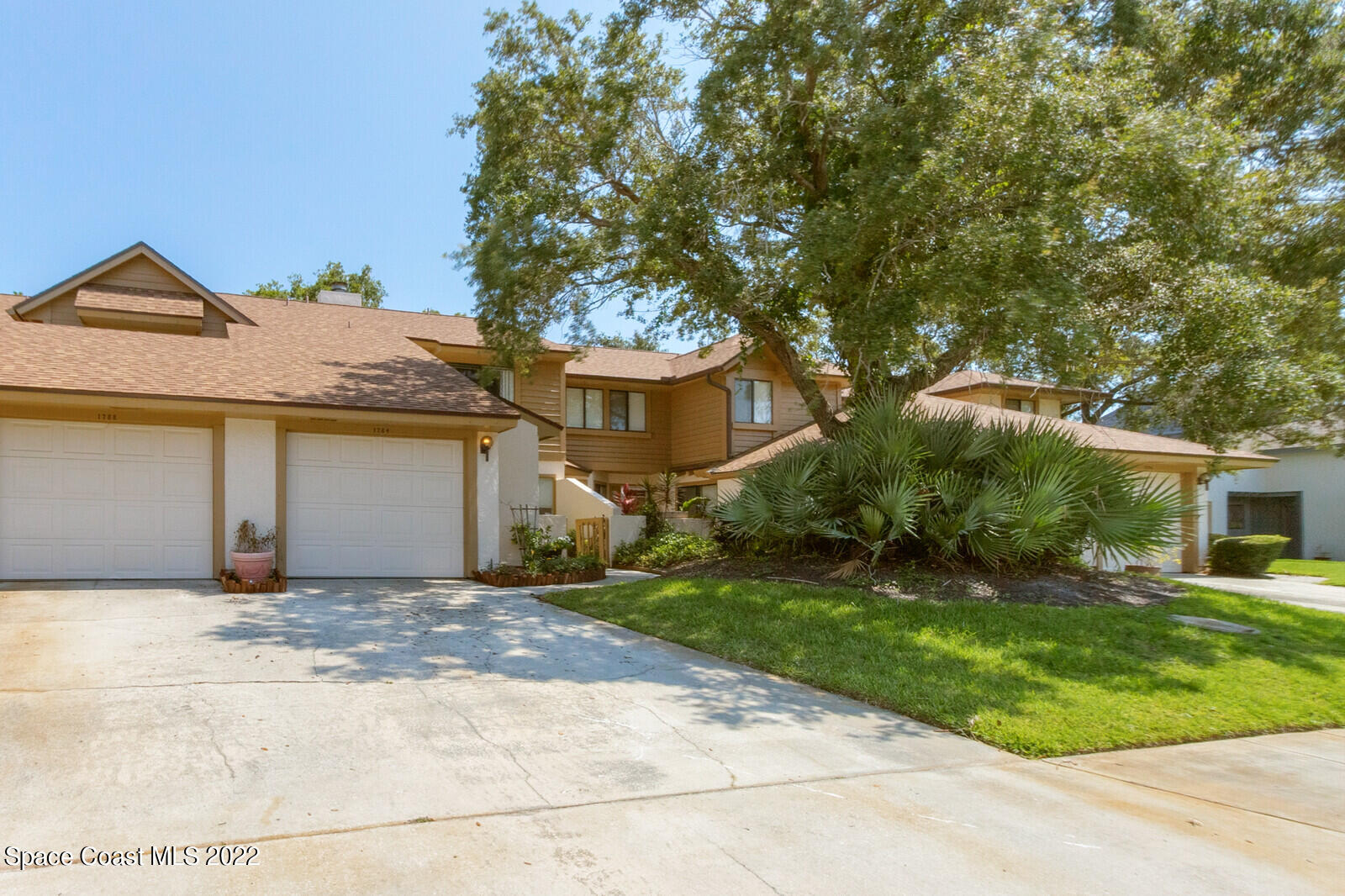 1784 Quail Trail Melbourne, FL 32935 - Photo 2 of 40 a view of a white house next to a yard with potted plants and large trees