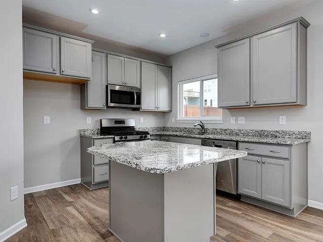 a kitchen with stainless steel appliances granite countertop a stove a sink and a microwave