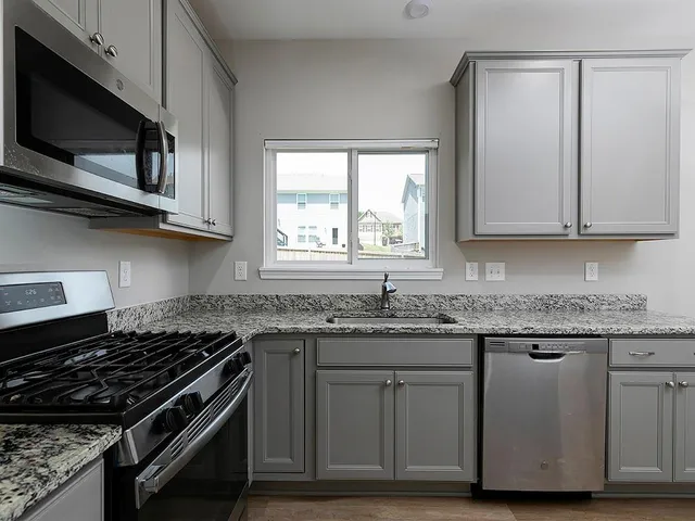 a kitchen with granite countertop wooden cabinets and a stove top oven