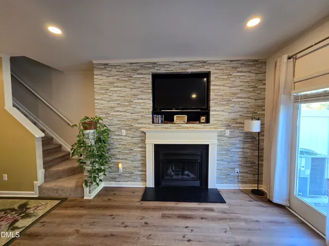 a living room with a fireplace a flat screen tv and a window