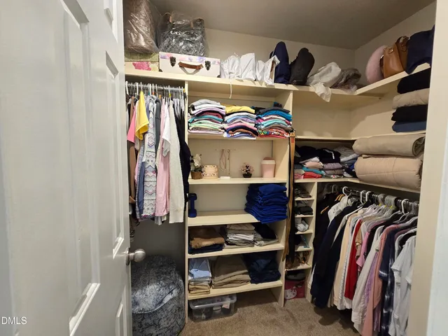 a view of walk in closet with clothes and shoes