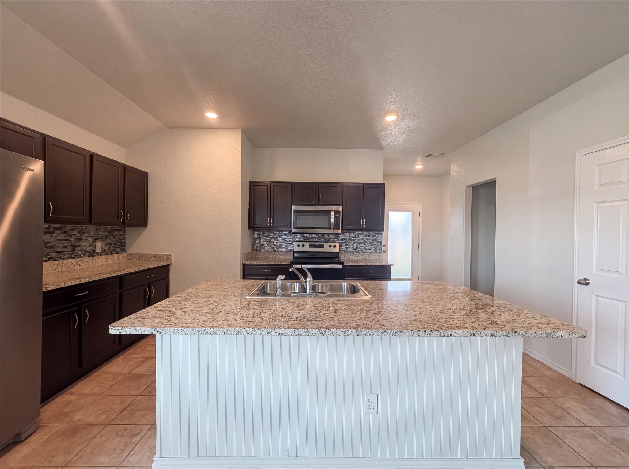 Polished granite countertops and dark wood cabinets anchor this functional culinary space.