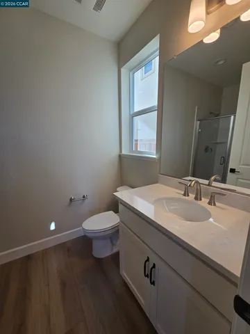 a bathroom with a granite countertop sink a toilet and a window