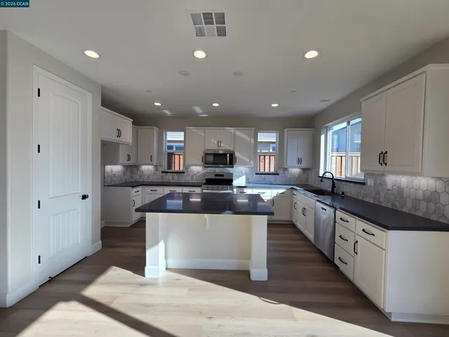 a large kitchen with stainless steel appliances lots of counter space sink and a refrigerator