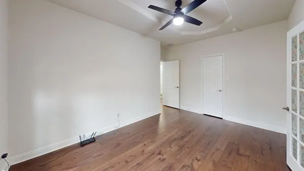 an empty room with wooden floor fan and windows