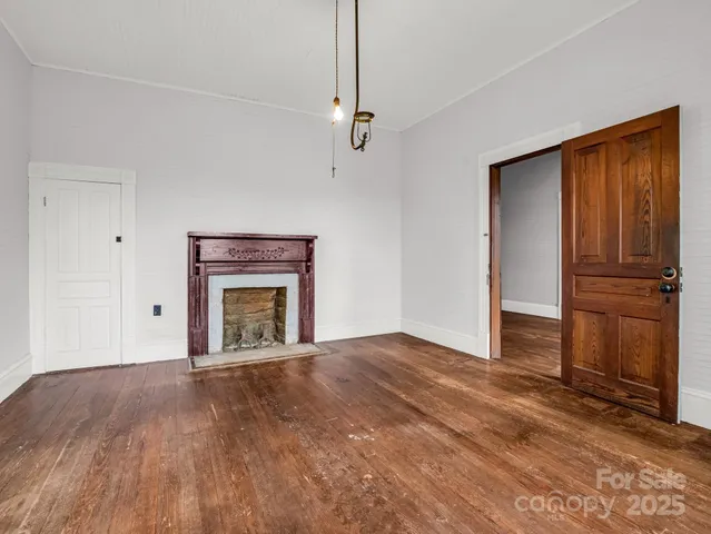a view of empty room with wooden floor and fireplace