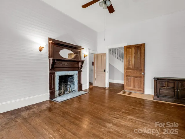 a view of an empty room with wooden floor fireplace and a window