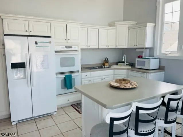 a kitchen with stainless steel appliances a white table and chairs in it