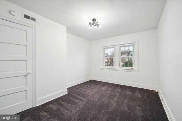 a view of empty room with window and chandelier fan