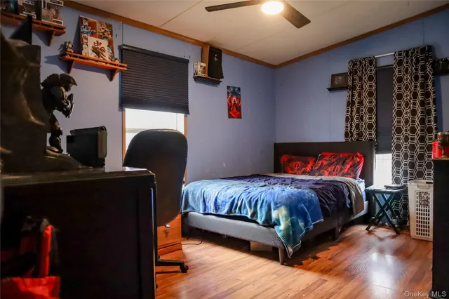 a bedroom with a bed and dresser with wooden floor