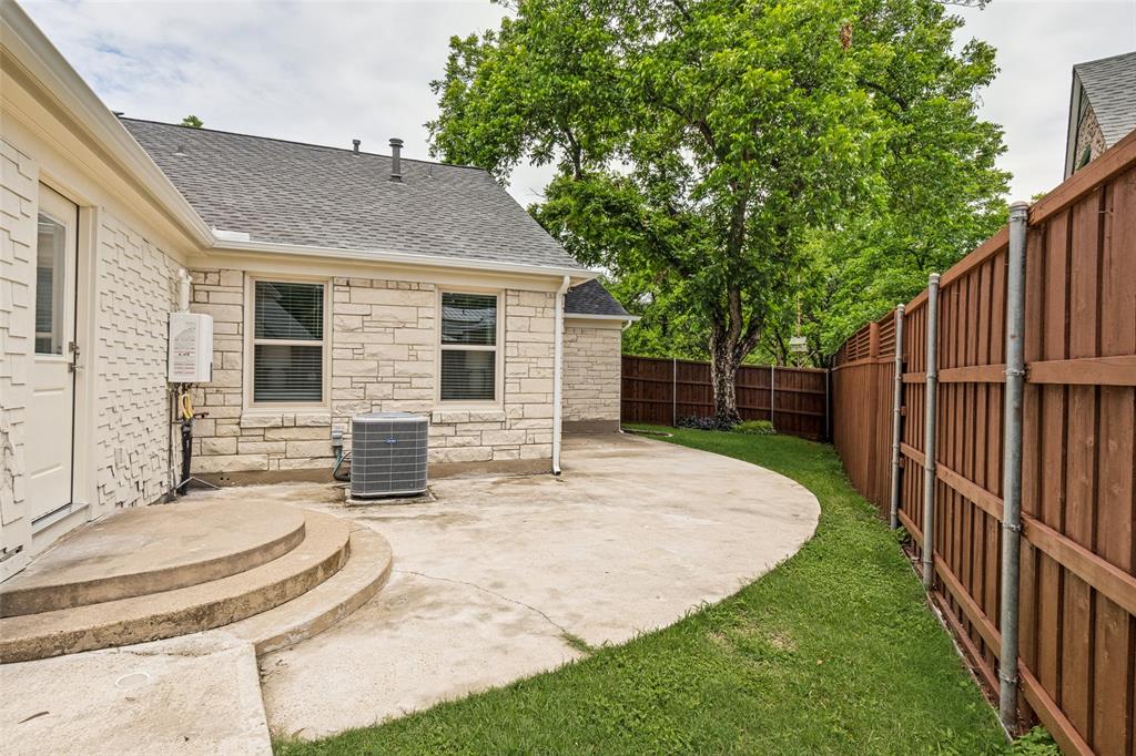 2006 Marydale Road Dallas, TX 75208 - Photo 38 of 40 Private backyard featuring a curved concrete patio, manicured lawn, and a tall wooden privacy fence