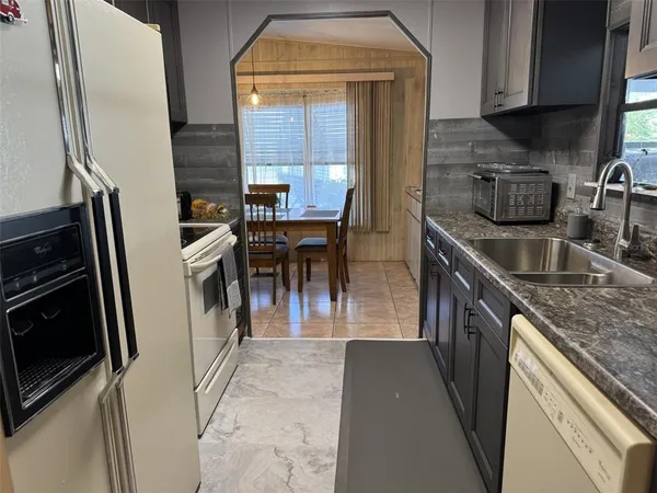 a kitchen with stainless steel appliances granite countertop a refrigerator a stove and a sink with wooden cabinets