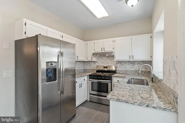 a kitchen with stainless steel appliances granite countertop a refrigerator stove and oven