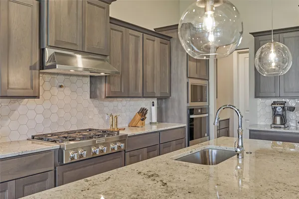 a kitchen with granite countertop a stove a sink and a wooden cabinets
