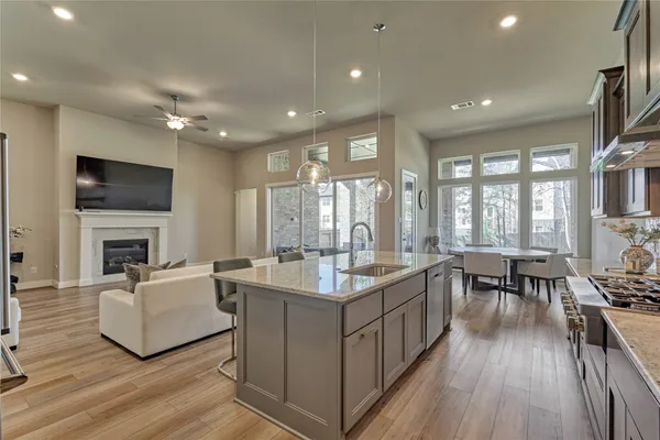 a living room with stainless steel appliances granite countertop sink stove and wooden floor