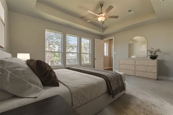 a spacious bedroom with a bed next to a window and a chandelier