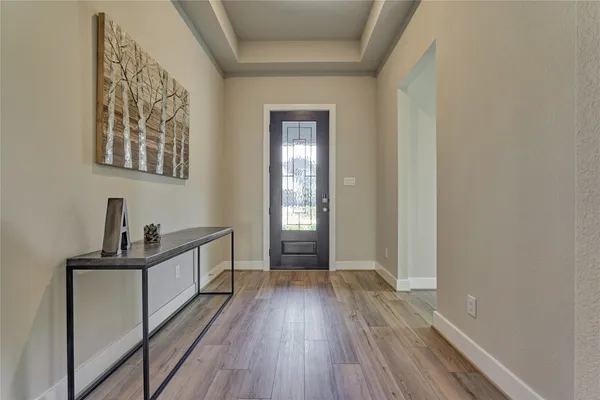 a view of a hallway to a room with wooden floor and stairs