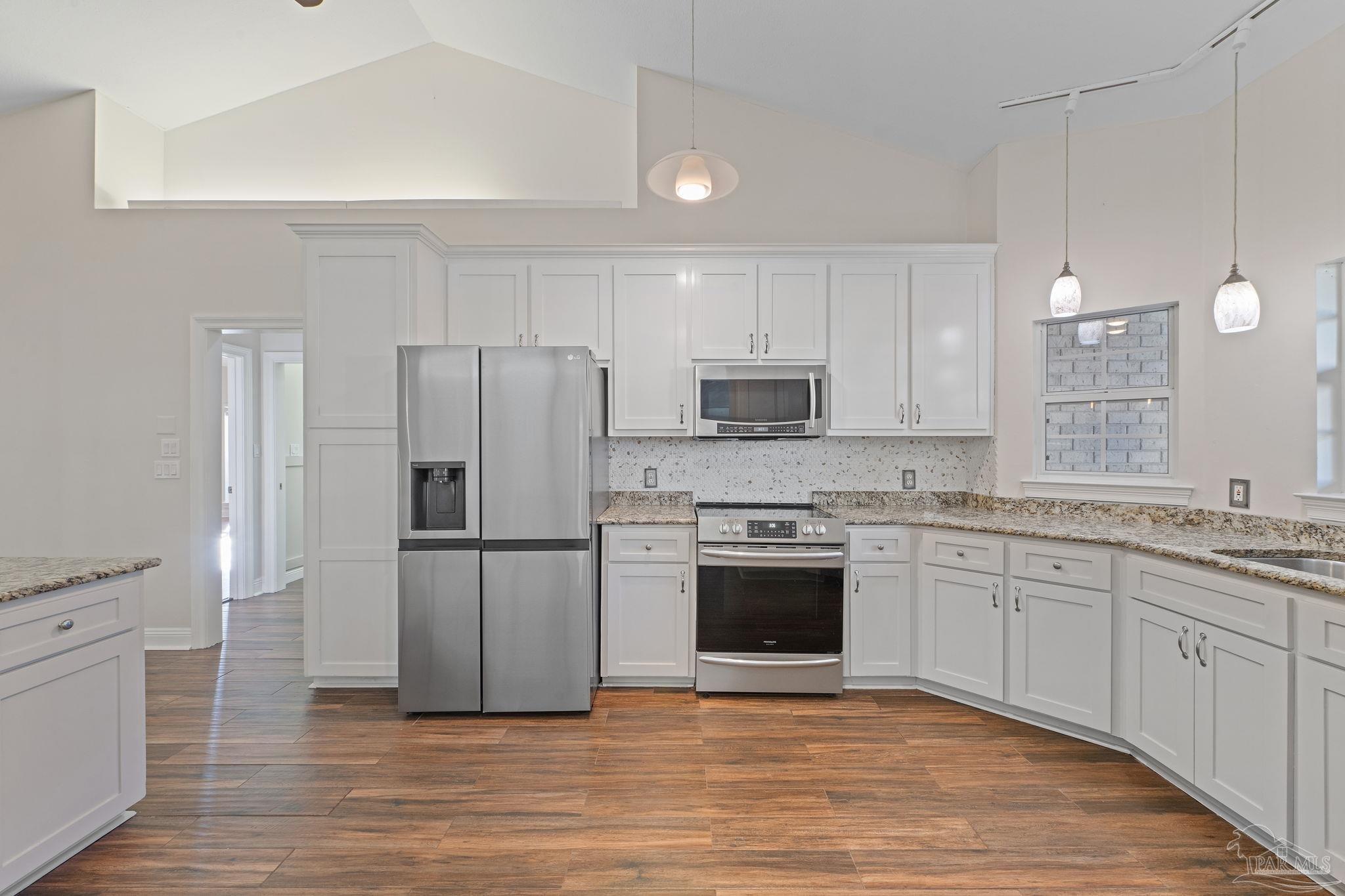 4149 Chartwell Street Pace, FL 32571 - Photo 12 of 49 a kitchen with granite countertop a refrigerator stove a sink and white cabinets