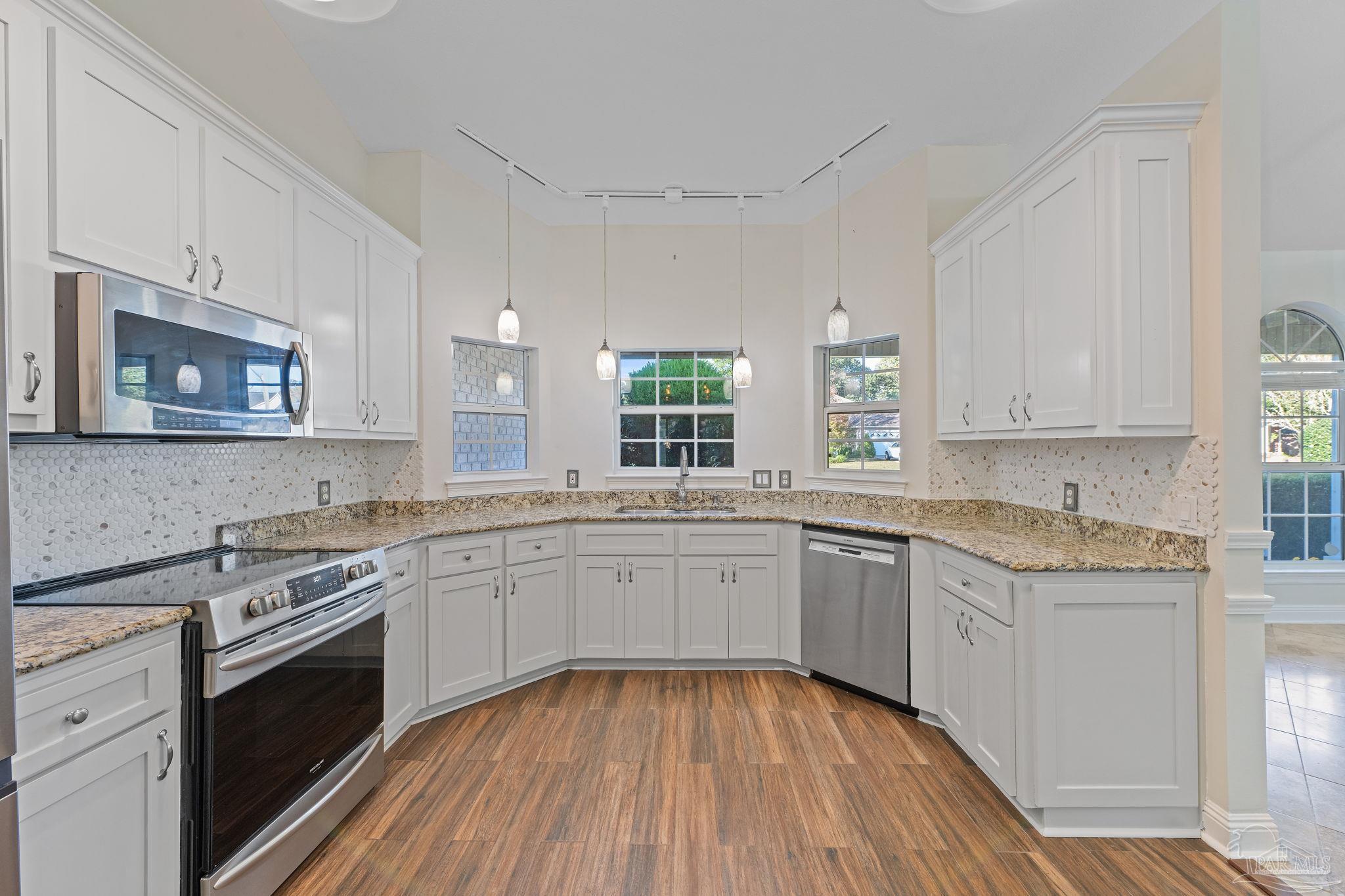 4149 Chartwell Street Pace, FL 32571 - Photo 13 of 49 a kitchen with a sink stove cabinets and wooden floor