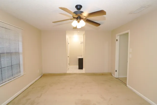 a view of an empty room with a chandelier fan