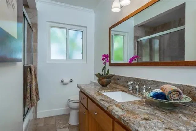 a bathroom with a granite countertop sink a toilet and mirror